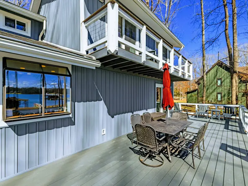 Lower Deck Dining - An outdoor dining set with a red umbrella on the lower deck provides a shaded spot for meals with lake views.