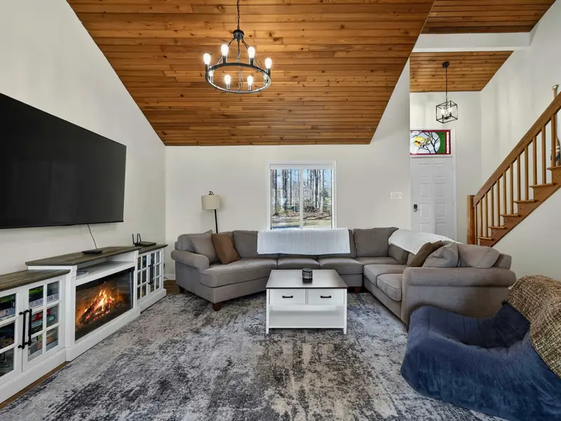 Living Room - Board games fill the media cabinet below the TV, with the sectional and vaulted ceiling creating a welcoming space for the whole group.