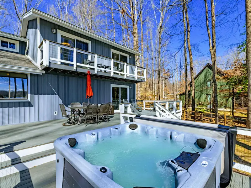 Hot Tub and House - The full rear of the house rises behind the hot tub, with the upper balcony and main deck creating a layered outdoor living space.
