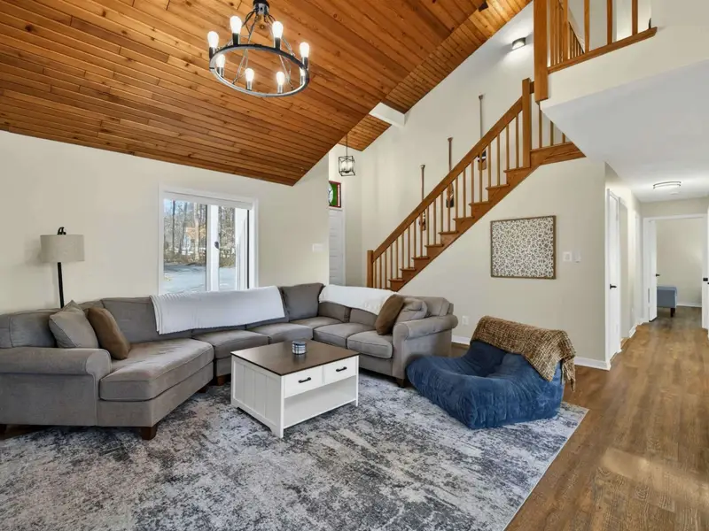 Living Room - From the sectional, the staircase leads up to the bedrooms while French doors open onto the deck with lake views beyond.