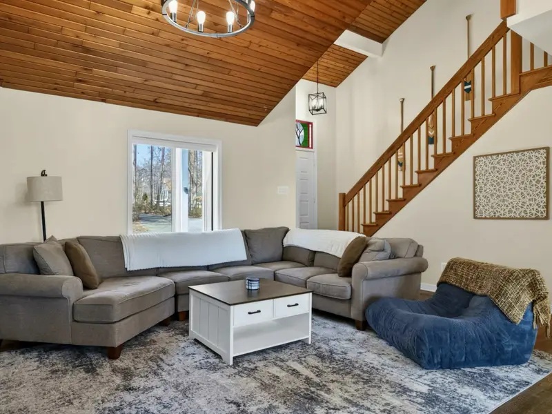 Living Room - A plush bean bag chair and oversized sectional offer plenty of seating, with the staircase, French doors, and stained glass accenting the open layout.