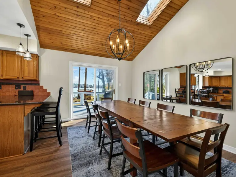 Dining Table - Mirrors and warm wood tones frame the table, with sliding doors offering a straight-through view to the deck and lake beyond.