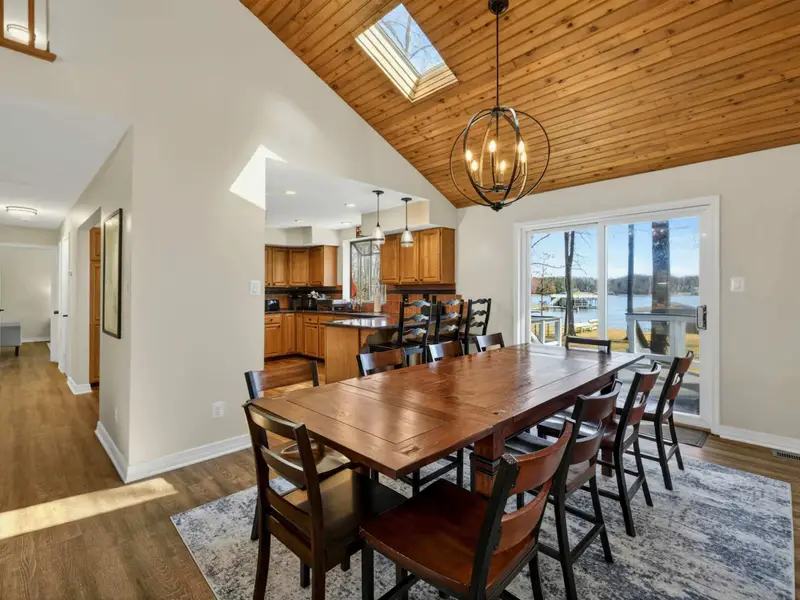 Dining and Lake View - Sliding glass doors open from the dining area to the deck, where the lake shimmers through the trees just outside.
