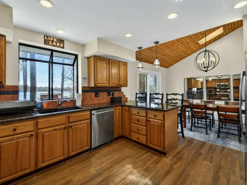 Kitchen to Dining - From the kitchen, the bar seating and dining table flow together under the vaulted wood ceiling, keeping the whole group connected.