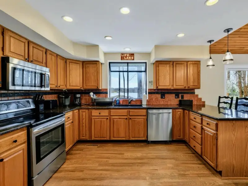Kitchen - The full U-shaped layout gives the cook plenty of counter space, with a lake-view window over the sink and a 'Life is Better at the Lake' sign overhead.