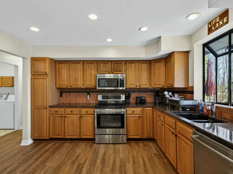 Kitchen - Generous counter space, a laundry closet just off the kitchen, and a lake-view window make this a practical, well-stocked space for group meals.