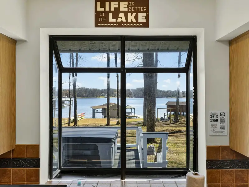 Kitchen View - The 'Life is Better at the Lake' sign frames a bay window looking straight out to the dock, boathouse, and water beyond.