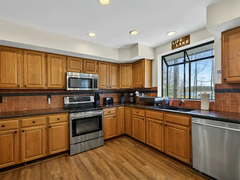 Kitchen Detail - A large bay window over the sink brings in lake views while you prep, with stainless dishwasher and granite counters completing the setup.