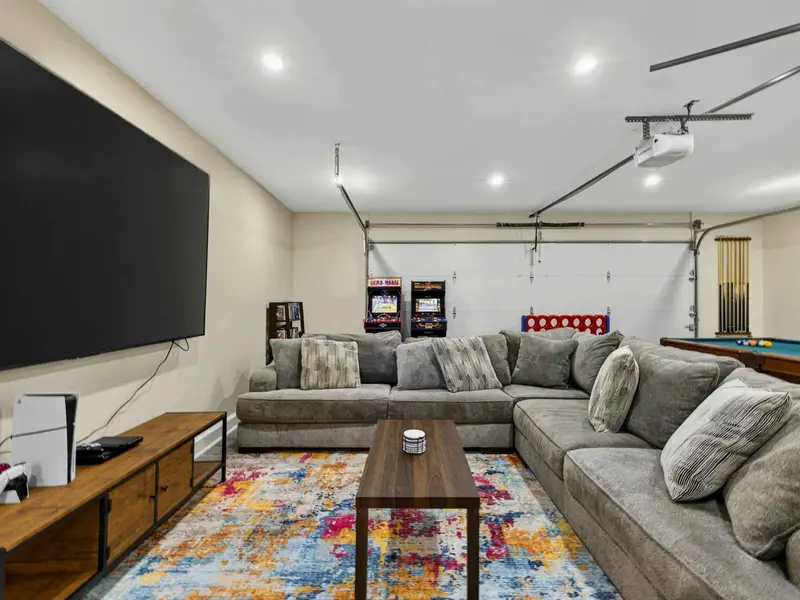 Game Room - A 100-inch TV with PS5 and a deep sectional anchor one end, while arcade games, Connect 4, and the pool table fill the rest of this entertainment hub.