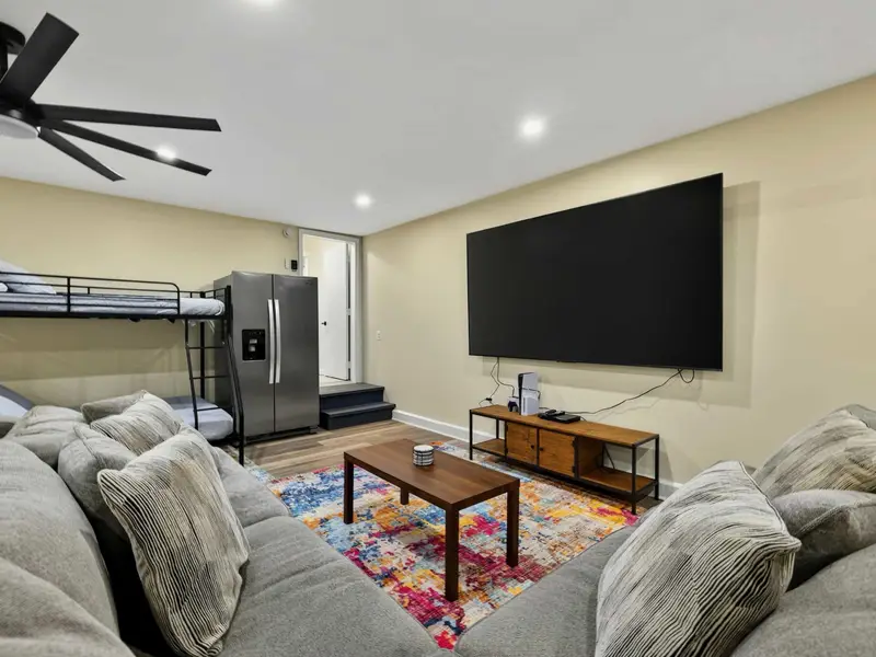 Game Room Lounge - The sectional faces the 100-inch TV with a PS5 ready to go, while bunk beds and a fridge sit behind for all-day hangouts.