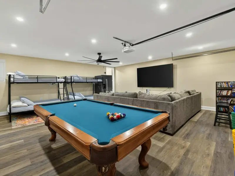 Game Room - From the bunk bed side, the pool table, massive TV, and deep sectional fill the space, with arcade games lining the far wall.
