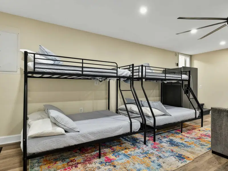 Bunk Beds - Two sets of twin-over-full metal bunk beds on a colorful rug provide sleeping space right in the action of the game room.