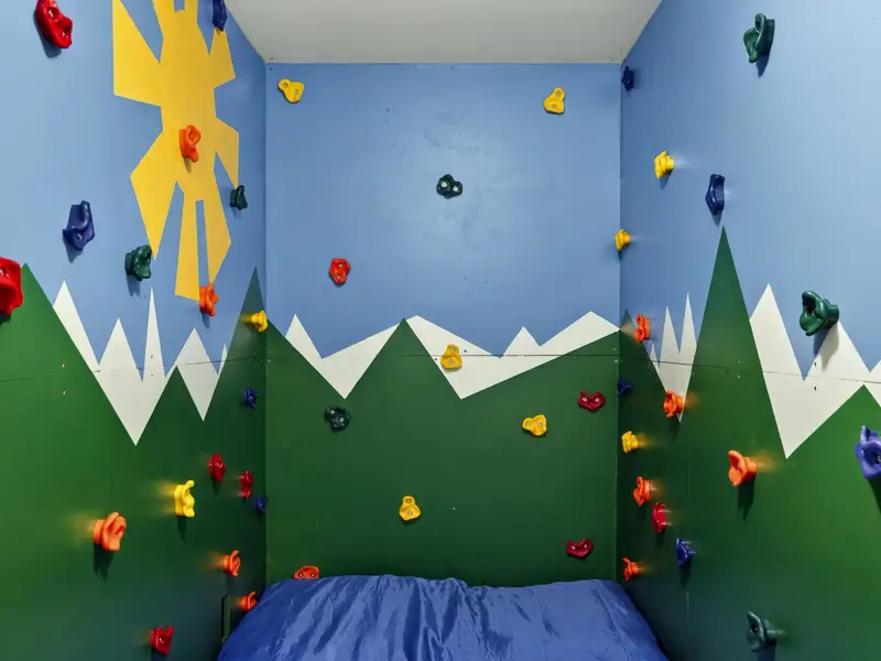 Climbing Wall Detail - Painted mountains and a sunshine mural surround the holds, making this climbing room a highlight for younger guests.