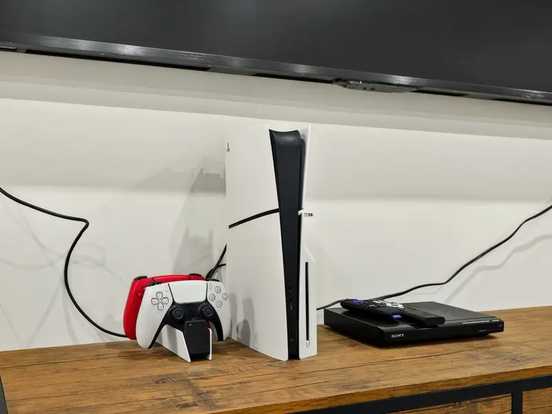 PS5 Gaming - A PlayStation 5 with controllers sits beneath the 100-inch TV, ready for gaming sessions on the big screen.