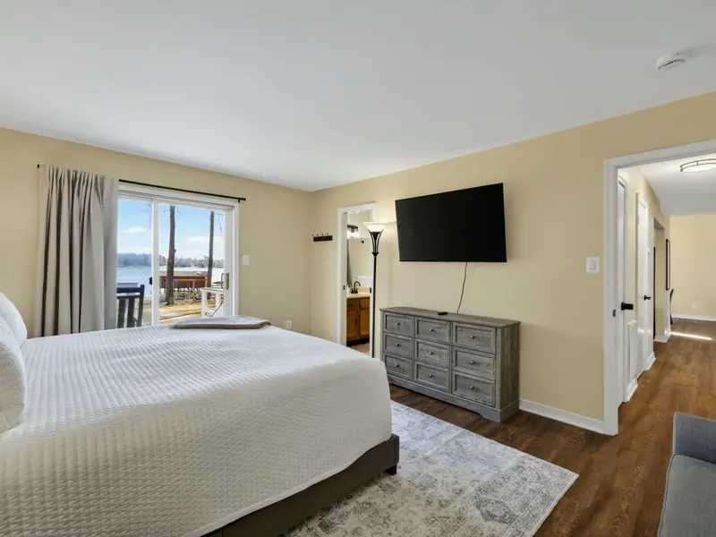 Primary Suite - A wall-mounted TV, gray dresser, and sliding door to the deck give the primary bedroom everything needed for a restful retreat.