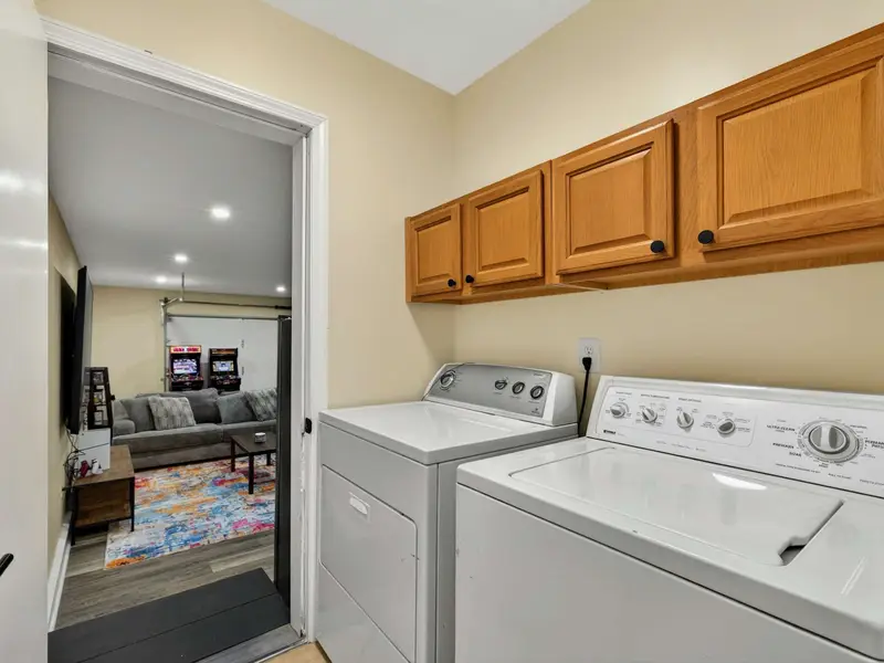 Laundry - Full-size washer and dryer with storage cabinets above, located right next to the game room for easy access.
