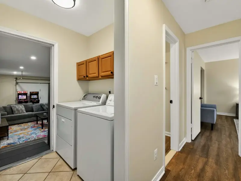 Laundry Nook - A washer and dryer with oak upper cabinets sit in a hallway nook between the game room and main-level bedroom, keeping laundry convenient.
