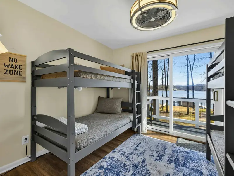 Bunk Room - Two sets of twin-over-twin bunks, a playful 'No Wake Zone' sign, and a sliding door to the balcony with lake views.