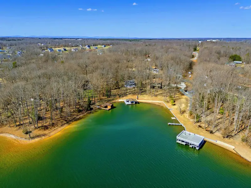 Aerial View - The full waterfront from above, showing the boathouse, sandy beach, and protected cove.