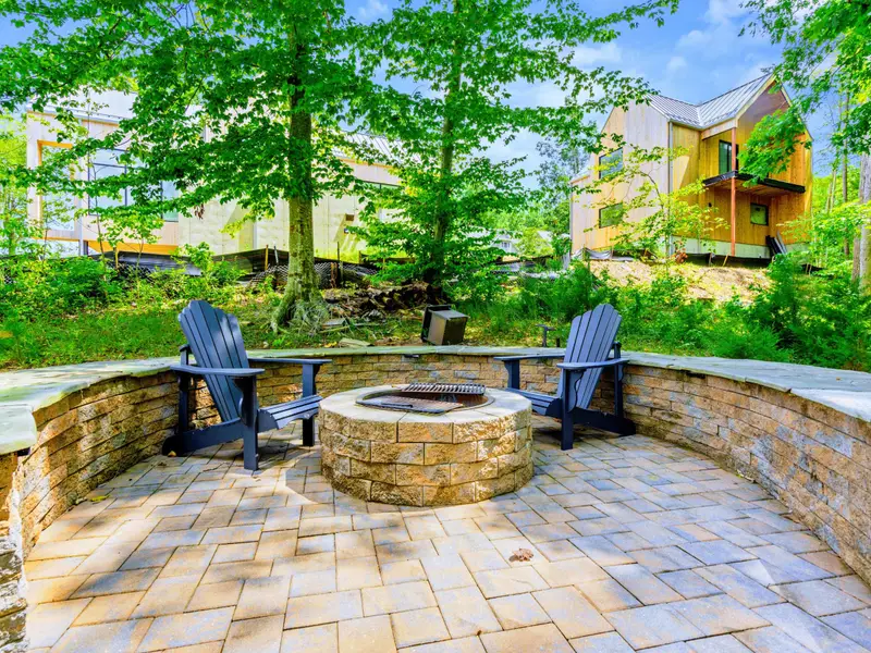 Built-in stone seating around the fire pit, with the lake just steps below. A natural gathering place that keeps the evening going.