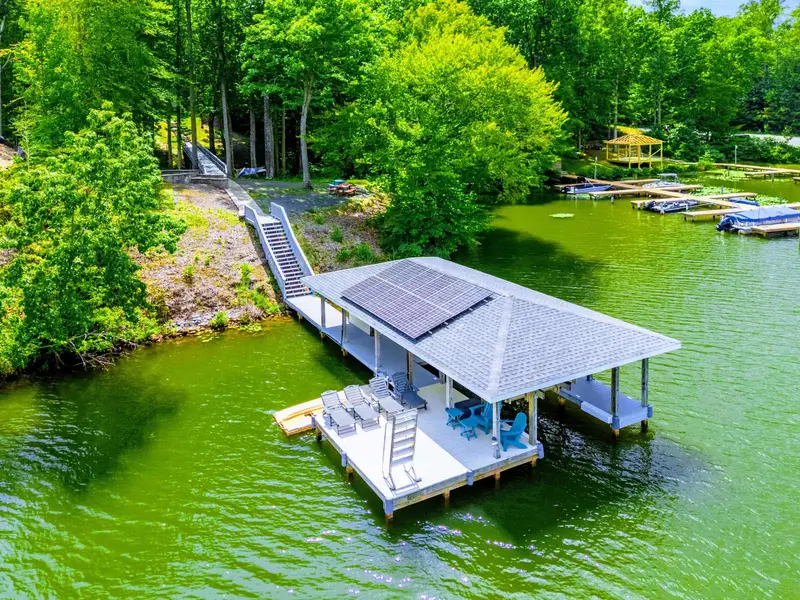 The full backyard from above: dock, pavilion, fire pit, terraced steps, and mature trees framing the shoreline.