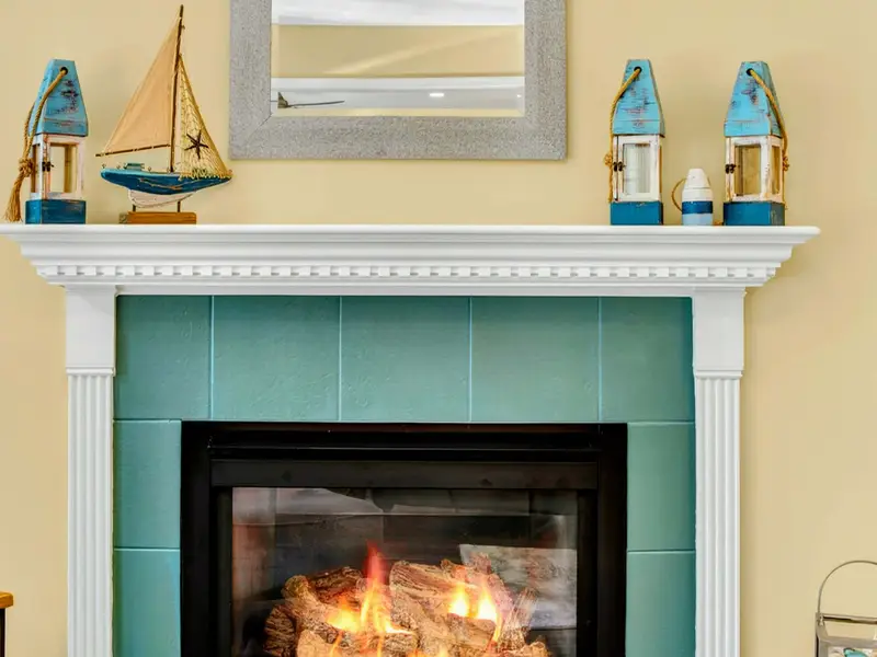 Turquoise tile fireplace with nautical touches on the mantel. The details make it feel like a lake house should.