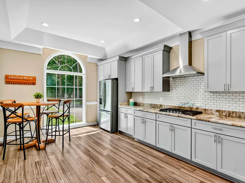 An arched window fills the kitchen with morning light. The tile backsplash adds a clean, bright detail.