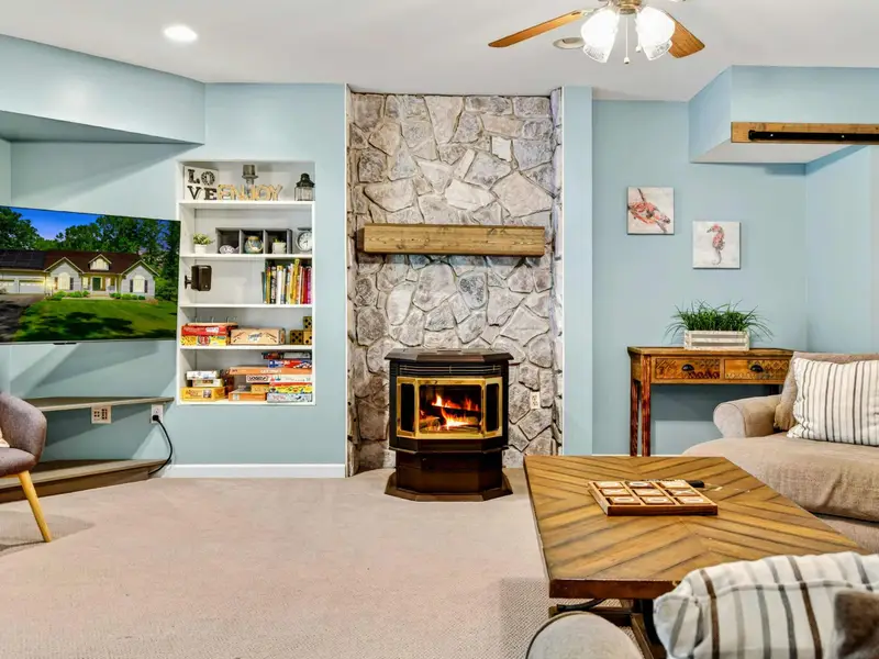 The lower level game room: stone fireplace, deep sectional, and room to spread out. A second living room that earns its name.
