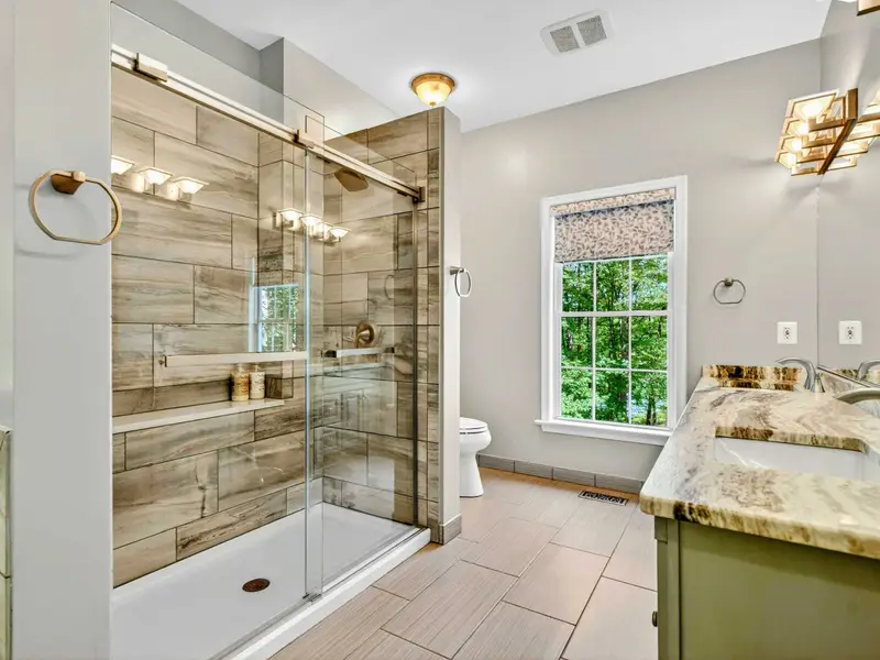 Glass-enclosed walk-in shower with bench seating. The en-suite bath in the primary feels like a spa.