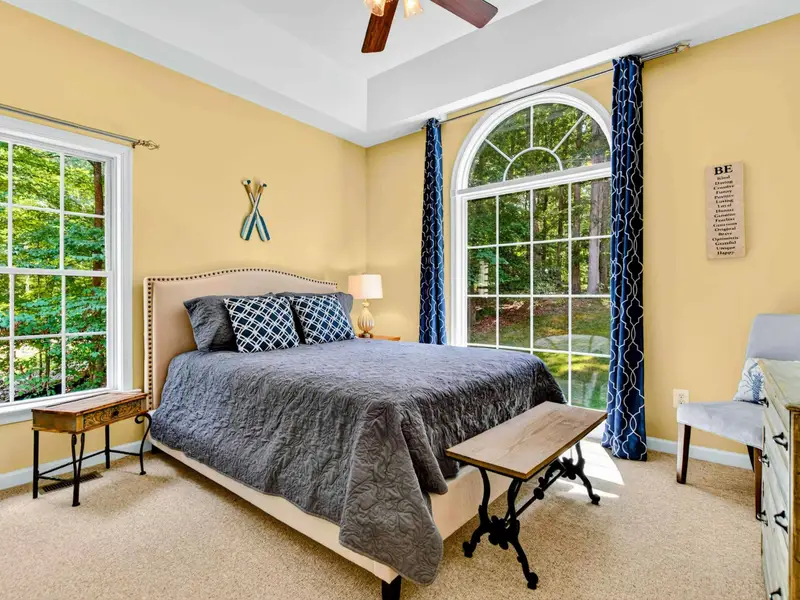 Bedroom 3: queen bed on the main level with blue patterned curtains and a calm, coastal feel.