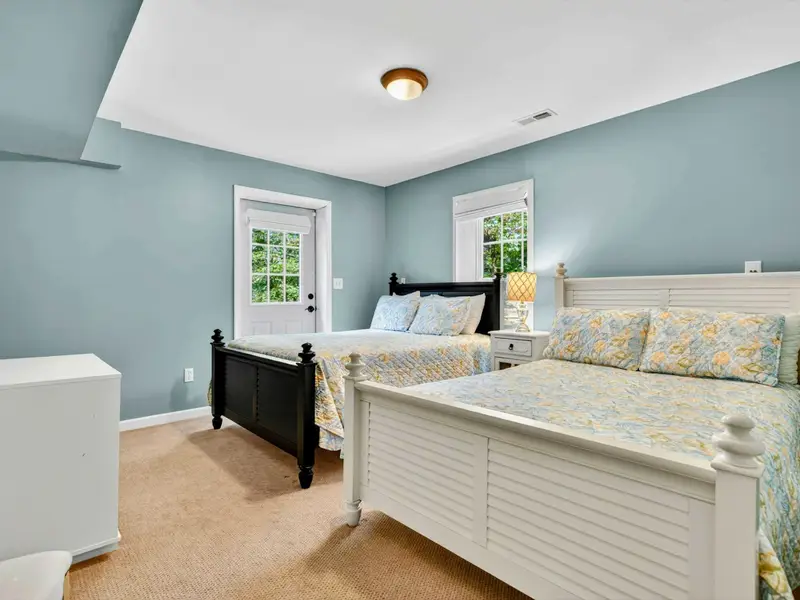 Bedroom 5 on the lower level. Two-tone bed frame and floral quilt with a walk-out to the yard.