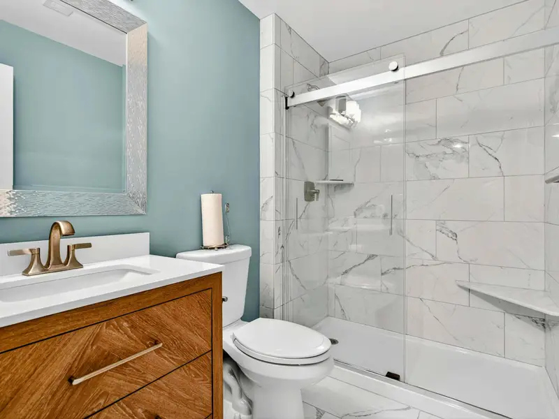 Full bathroom with wood vanity, tiled shower, and tub. Clean and well appointed for the lower level bedrooms.