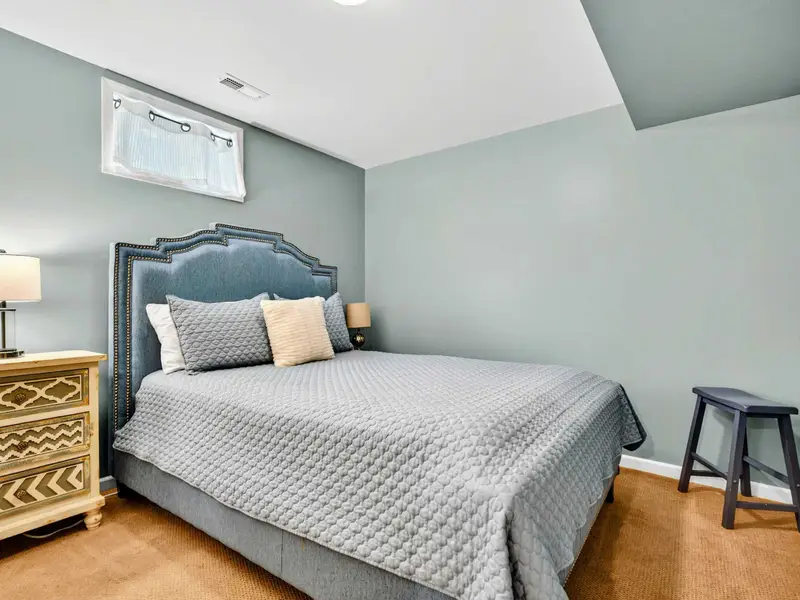 Bedroom 6 on the lower level: queen bed with a blue upholstered headboard. Simple, comfortable, ready.