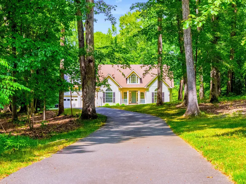 Hello Sunshine from the front: covered porch, stone accents, and a three-car garage. A warm welcome from the driveway.