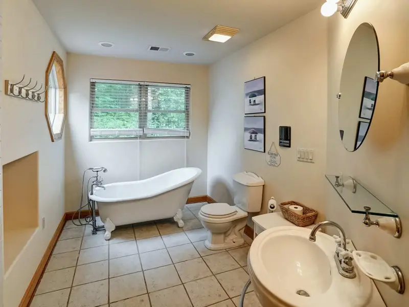 A Bath Worth the Climb - A clawfoot tub, pedestal sink, and round mirror bring boutique hotel charm to the loft.