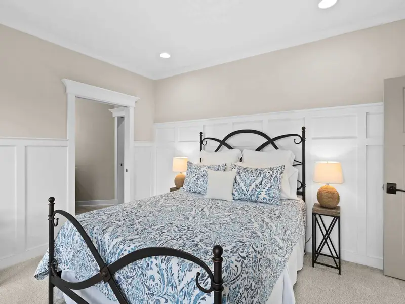 Queen Bedroom - A light-filled main-floor bedroom with wainscoting walls and a calm, cottage-style feel.