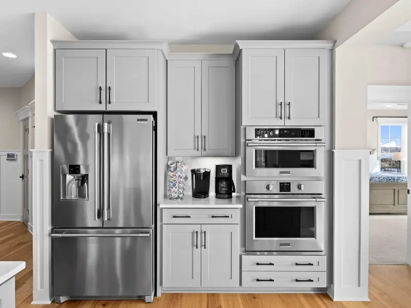 Kitchen - The appliance wall features a stainless French-door fridge, wall oven, and microwave flanked by floor-to-ceiling cabinetry.