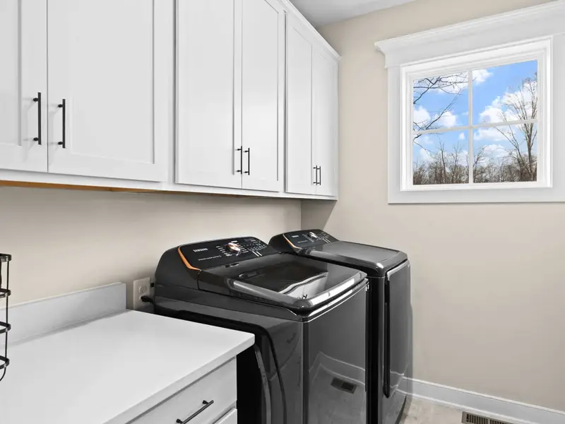 Laundry Room - Full-size washer and dryer with upper cabinetry and a window, tucked neatly off the kitchen.