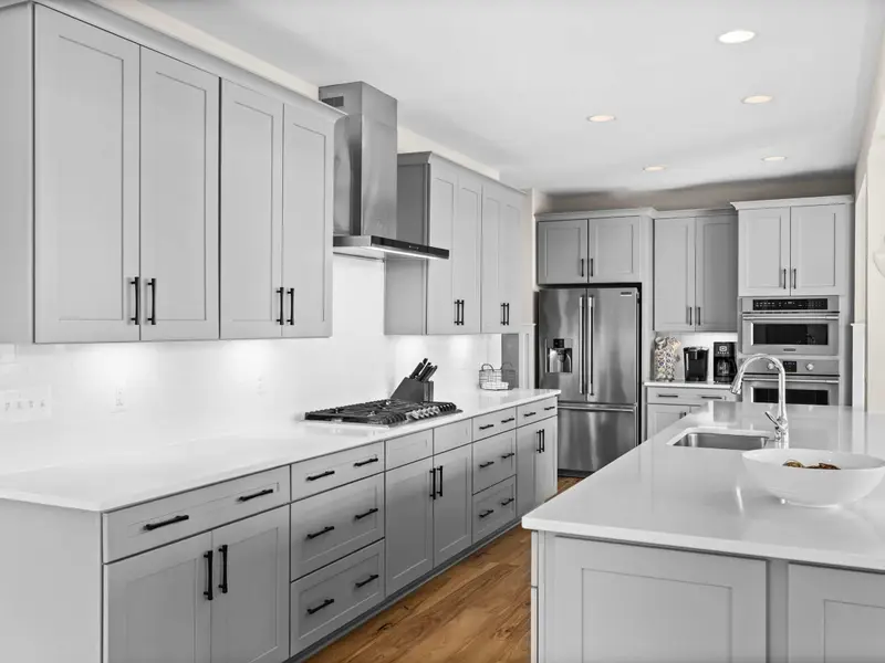 Kitchen - The kitchen island with quartz countertop and four leather bar stools, a natural gathering spot for guests.