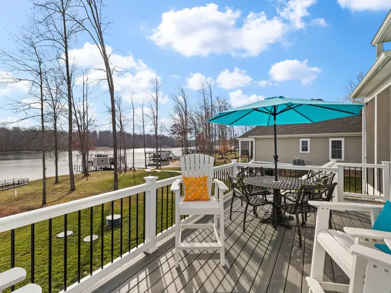 Deck - Adirondack chairs and a dining table with teal umbrella face the lake and boathouse, a deck made for long afternoons.