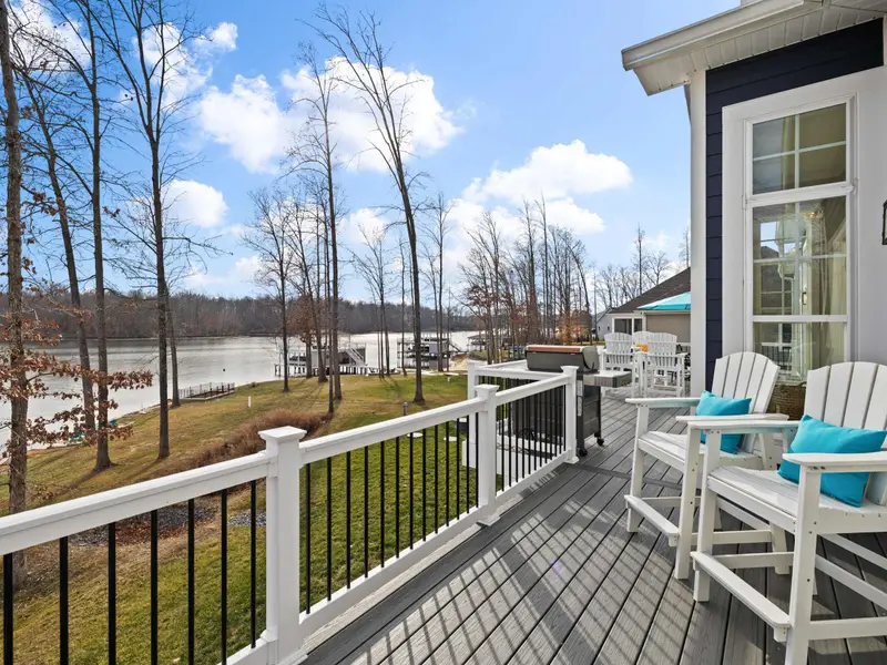 Deck - Adirondack chairs on the main deck look out over the lawn toward the lake and the open water beyond.