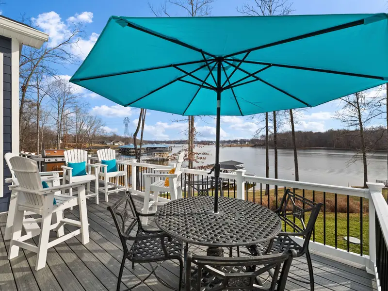 Deck - Outdoor dining with umbrella shade and bar seating, right off the great room with the lake as the backdrop.
