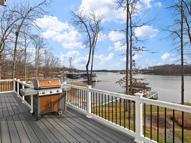 Deck - A gas grill at the ready with the lake and boathouse in the distance.
