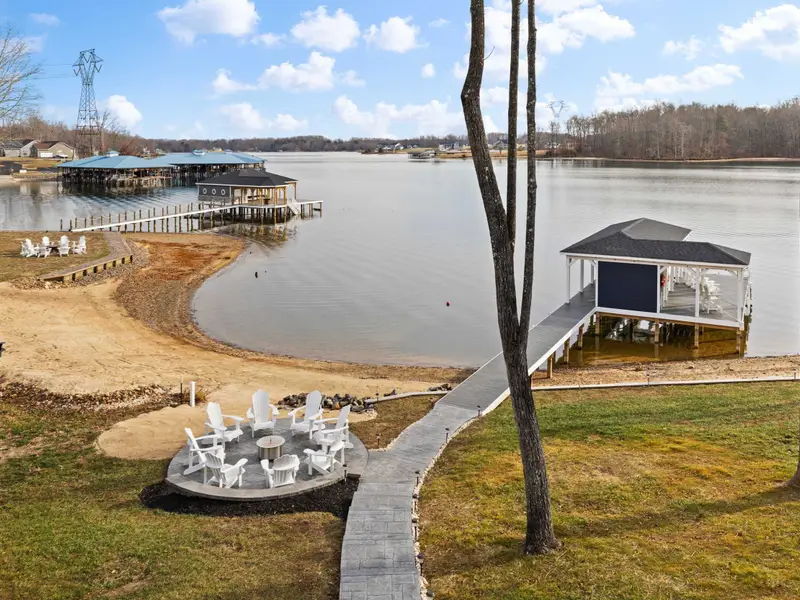Deck - An elevated view from the main deck shows the fire pit below, the dock path, and the boathouse over the water.