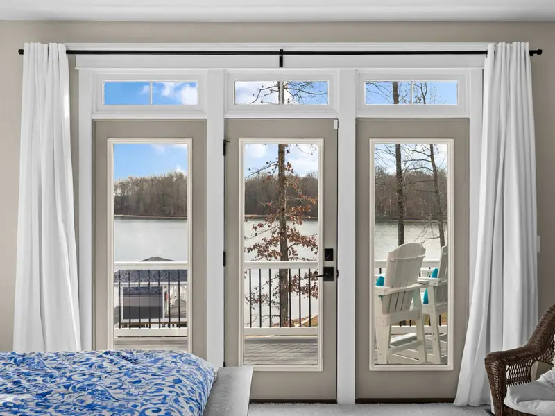 Primary Suite - French doors in the primary suite frame the lake and the deck, with an Adirondack chair already waiting.