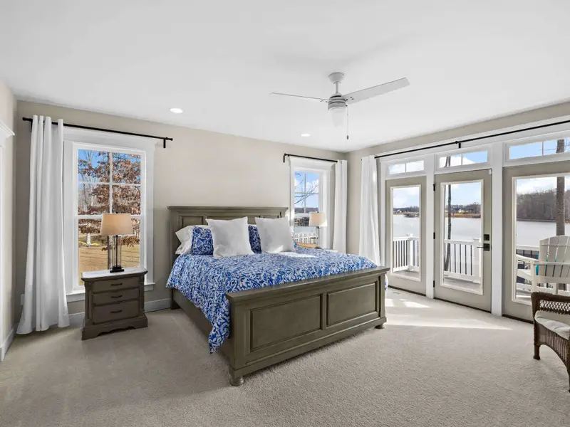 Primary Suite - A king bed with crisp blue-and-white bedding faces French doors that open directly to the lake-view deck.