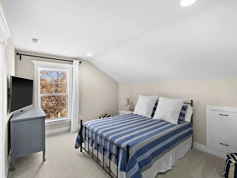 Queen Bedroom - An upper bedroom with queen bed, sloped ceiling, TV, and an en-suite just through the doorway.