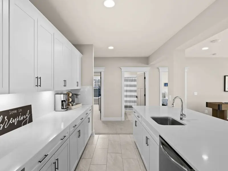 Lower Level Bar - White cabinetry, quartz countertop, and a full setup including a beverage fridge and coffee station.