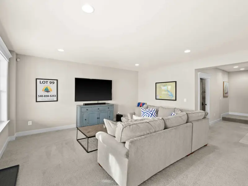 Lower Level Lounge - A comfortable lounge with sofa, TV on a teal credenza, and the game room just beyond.