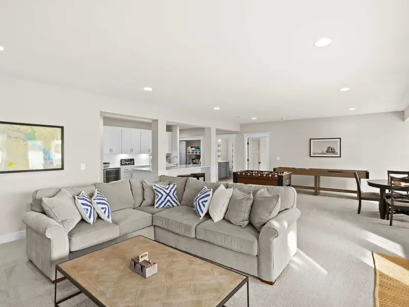 Game Room - Wide view of the lower level showing the lounge sofa and the game room with foosball and shuffleboard beyond.